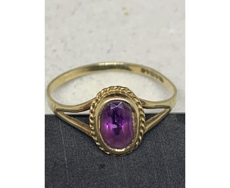 A 9 CARAT GOLD RING WITH A PURPLE STONE SIZE O/P 