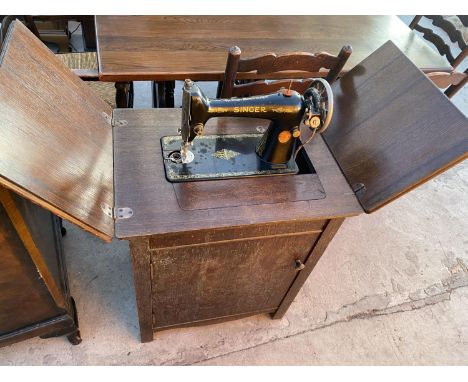 A VINTAGE SINGER SEWING MACHINE IN AN OAK CABINET 