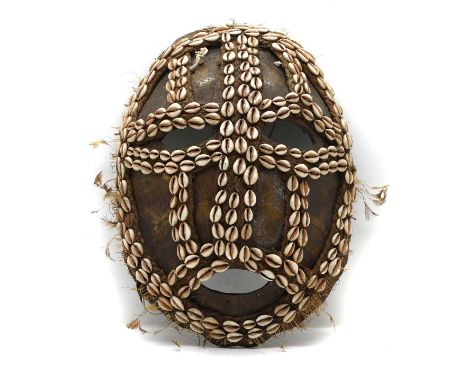 A Papua New Guinea turtle shell mask, 20th century, with applied cowrie shells, feathers, and straw30cm wide42.5cm highCondit