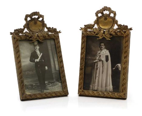 A pair of gilt bronze photograph frames early 20th century, the ribbon tied pediments over rope twist frames, with hinged res