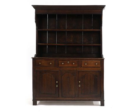 A small George III oak dresser, 18th century, the moulded cornice above two plate shelves with shaped ends, the lower section