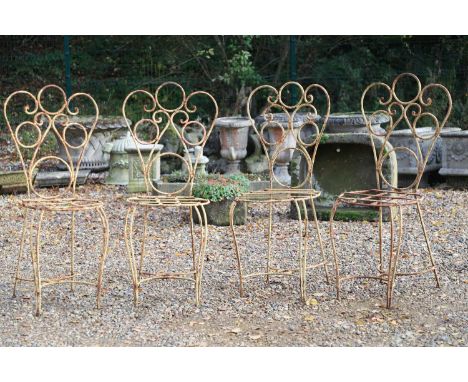 A set of four French wrought iron bistro chairs, 20th century,the scrolled heart form back above circular seat on cabriole su