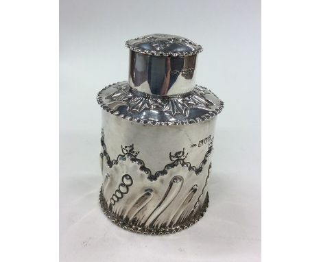 An Edwardian silver tea caddy of half fluted design with scrolls, flowers and crimped rim with lift-off cover. London. By CCP
