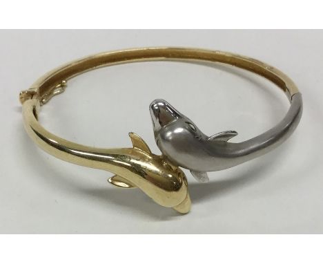 A stylish 14 carat two coloured gold bangle decorated with dolphins. Approx. 16.7 grams. Est. £350 - £400