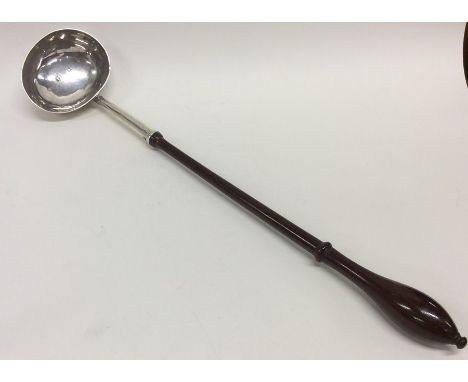 A Georgian silver toddy ladle on turned wooden handle. London. By IF. Approx. 38 cms long. Est. £120 - £150.