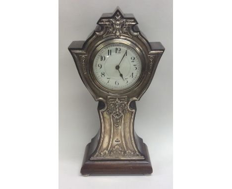 A tall Edwardian silver mantle clock decorated with flowers and leaves. Birmingham. By GS&amp;J. Est. £100 - £150.