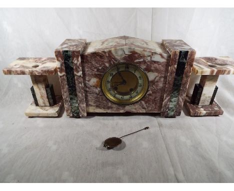 An Art Deco styled clock set in pink and white veined marble and green marble accents, the clock having a round plate hour an