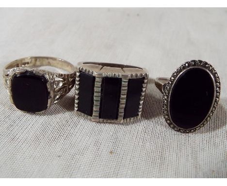 Two gentlemen's silver rings set with onyx and one further silver dress ring set with onyx and marcasite 