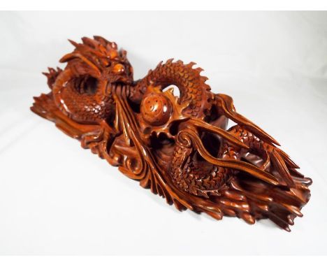 A hard wood carving depicting the dragon chasing the flaming pearl, 13cm (h) x 43cm (l) - Est £50 - £80