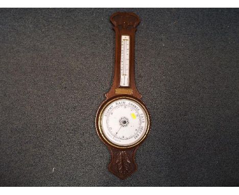 An early 20th century oak cased banjo-style aneroid wall barometer, the dial and mercury thermometer scale in white enamel, c