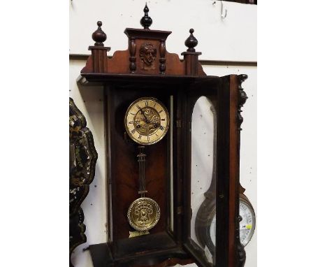 A spring-driven wall mounted Vienna style wall clock, the walnut case flanked by turned columns, surmounted by a decorative p