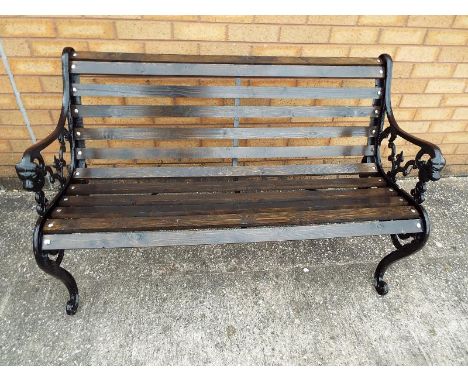 A cast iron garden bench with lion head and wooden slats 77cm x 126cm x 66cm