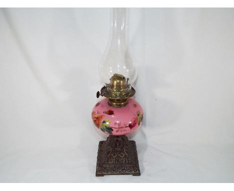 An oil lamp, the reservoir painted with roses on a pink ground, 57cm (h)