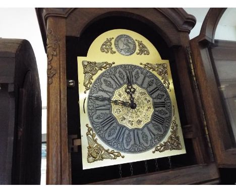 An oak cased longcase clock in the Continental style, the oak case having carved decoration and glazed door to display the pe