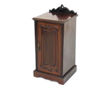 An Edwardian mahogany pot cupboard, with heavily carved cornice raised above a lattice panelled door, on bracket feet, 78cm h