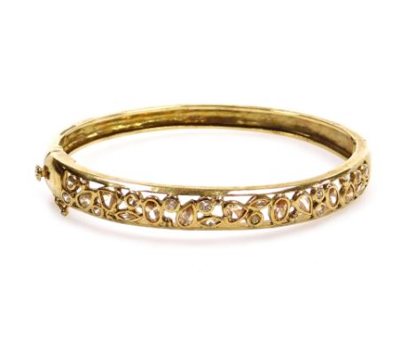 A yellow metal and stone set bangle, in an openwork design, on a snap clasp, 20.7g.