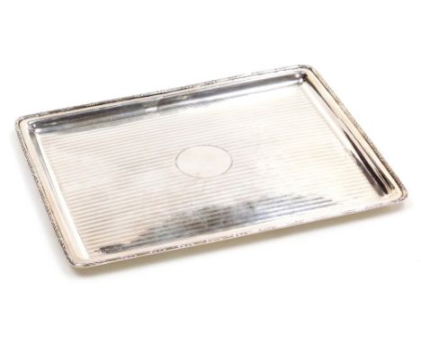 A George V silver tray, of rectangular form, with a leaf and raised line decorated border, engine turned decoration with circ