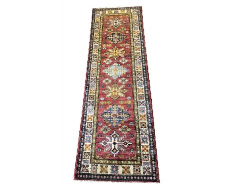 FINE KAZAK RUNNERS a near pair, 192cm x 62 and 190cm x 60cm, row of geometric medallions on a ruby field within complimentary