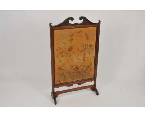 An Edwardian mahogany framed embroidered fire screen, decorated with an intricate study of flowers and foliage, the frame sur