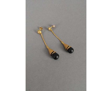 A pair of black stone set drop ear pendants, the polished black drops mounted within yellow metal textured cones suspended fr