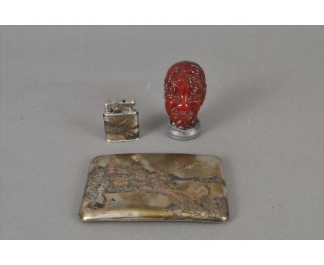 A small cased Japanese engraved cigarette case and lighter duo, together with a simulated amber Chinese bust, formed from num