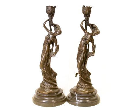 Two Art Nouveau style bronze candlesticks in the form of nymphs in diaphanous clothing supporting a sconce of flowerhead form