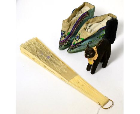 A Steiff cat, with original paper label and arched back; together with a pair of Chinese embroidered shoes; and a lace fan wi