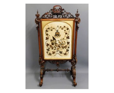 A large 19thC. rosewood ornate firescreen with raised work on silk with central coat of arms, 60.75in high x 32.25in wide 