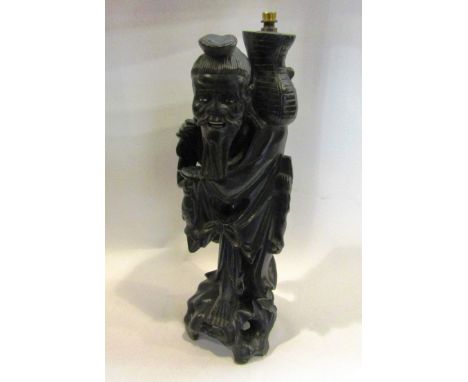 A carved Oriental ebonised gentleman lamp base, 36cm high   
