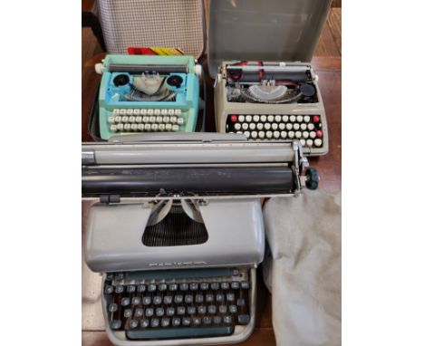 Three vintage typewriters: a Smith Corona Corsair circa 1970 in original case, a Remington Rand in original cover, and a chil