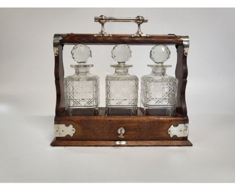 Limed oak tantalus containing three glass decanters. 33cm x 36cm x 13cm.