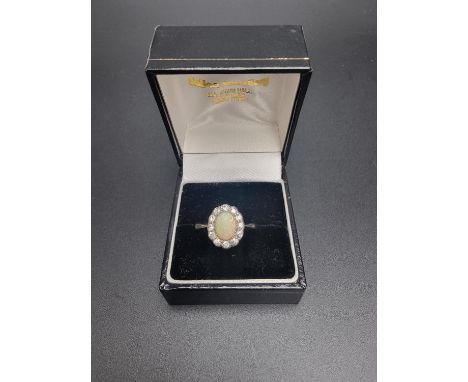 A yellow metal opal and diamond cluster ring, set oval cabochon opal surrounded by twelve diamonds, size S. 