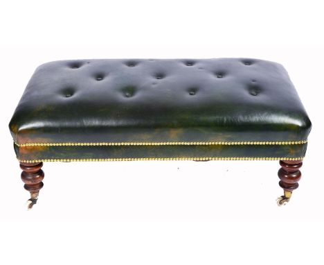 A GREEN LEATHER BUTTON UPHOLSTERED RECTANGULAR LOW STOOL with studded decoration and standing on turned tapering mahogany leg
