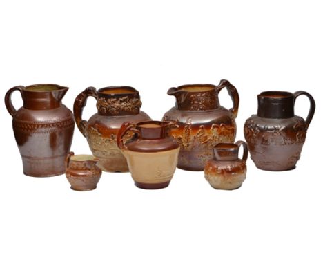 TWO 19TH CENTURY STONEWARE JUGS, relief moulded with hunting and country scenes with greyhound handles, 23cm high, another si