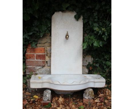AN OTTOMAN WHITE MARBLE FOUNTAIN with carved shaped basin and a back stand with relief carved Kufic script and brass tap in t