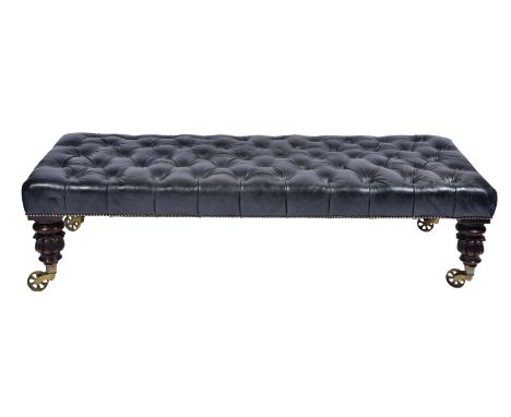 A BLACK LEATHER BUTTON UPHOLSTERED RECTANGULAR LOW STOOL standing on turned carved mahogany legs terminating in brass casters