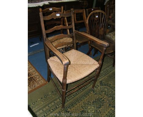 An Arts and Crafts framed ladder-back Elbow Chair with four shaped rungs to the back, shaped flat arms and rush seat, on turn