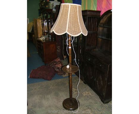 A 1940's Oak Standard Lamp with net style tapering shade, turned column with circular dish shelf and lower turned pedestal ba