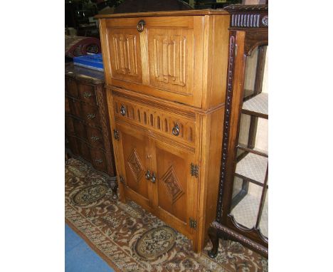 A Priory style light Oak Cocktail Cabinet, the upper section having two linen-fold panel fall and moulded edge lifting lid op