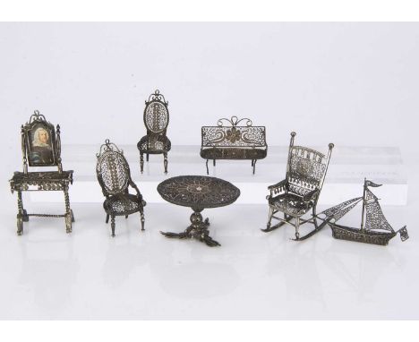 A set of white metal filigree dolls’ house furniture,  a rocking chair —2 1/4in. (6cm.) high; a circular table, a chair and a