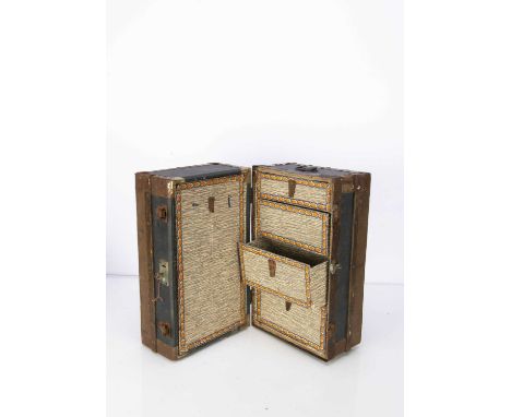 An early 20th century dolls’ cabin trunk,  of textured black oil-cloth, wooden bands, tinplate edges, handles and opening upr