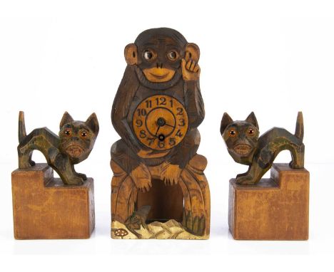 An amusing carved wooden monkey clock with moving eyes, probably German —9 3/4in. (25cm.) high; and a pair of carved wooden c