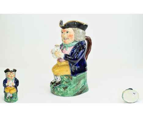 George lll Rare 18th Century Ralph Wood Type Toby Jug, seated with legs crossed, holding a jug in both hands, wearing a cobal