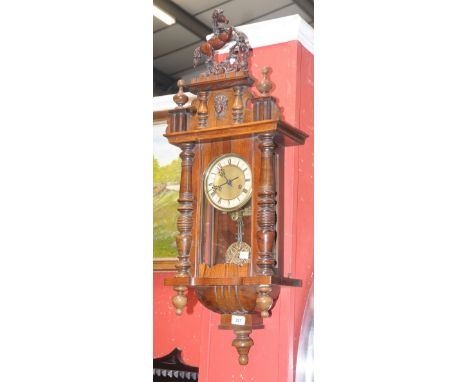 A Vienna wallclock, horse rampant pediment. enamelled chapter ring, Roman numerals, turned pilasters.