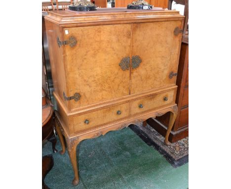 A reproduction walnut cocktail cabinet, caddy top, two quarter veneered doors over two short drawers, shaped apron, cabriole 