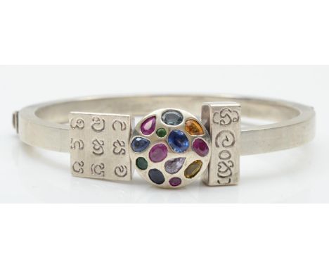 An unmarked silver and gemset hinged bangle, with three sliding charms, 67 x 62mm internals, 48gm 