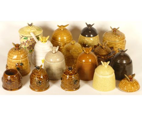 A collection of fourteen ceramic honey pots, with lids, in the form of beehives with a bee seated atop 