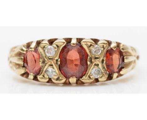 A vintage Edwardian style garnet three stone ring, brilliant cut diamonds between, N, 2.1gm 