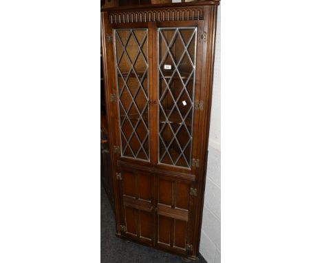 A floor standing corner cupboard, with leaded light glazed double doors above and panelled double doors below.