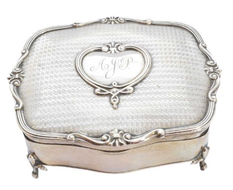 A George V silver trinket box, the engine turned hinged lid with central cartouche and scrolling border, raised on four feet 